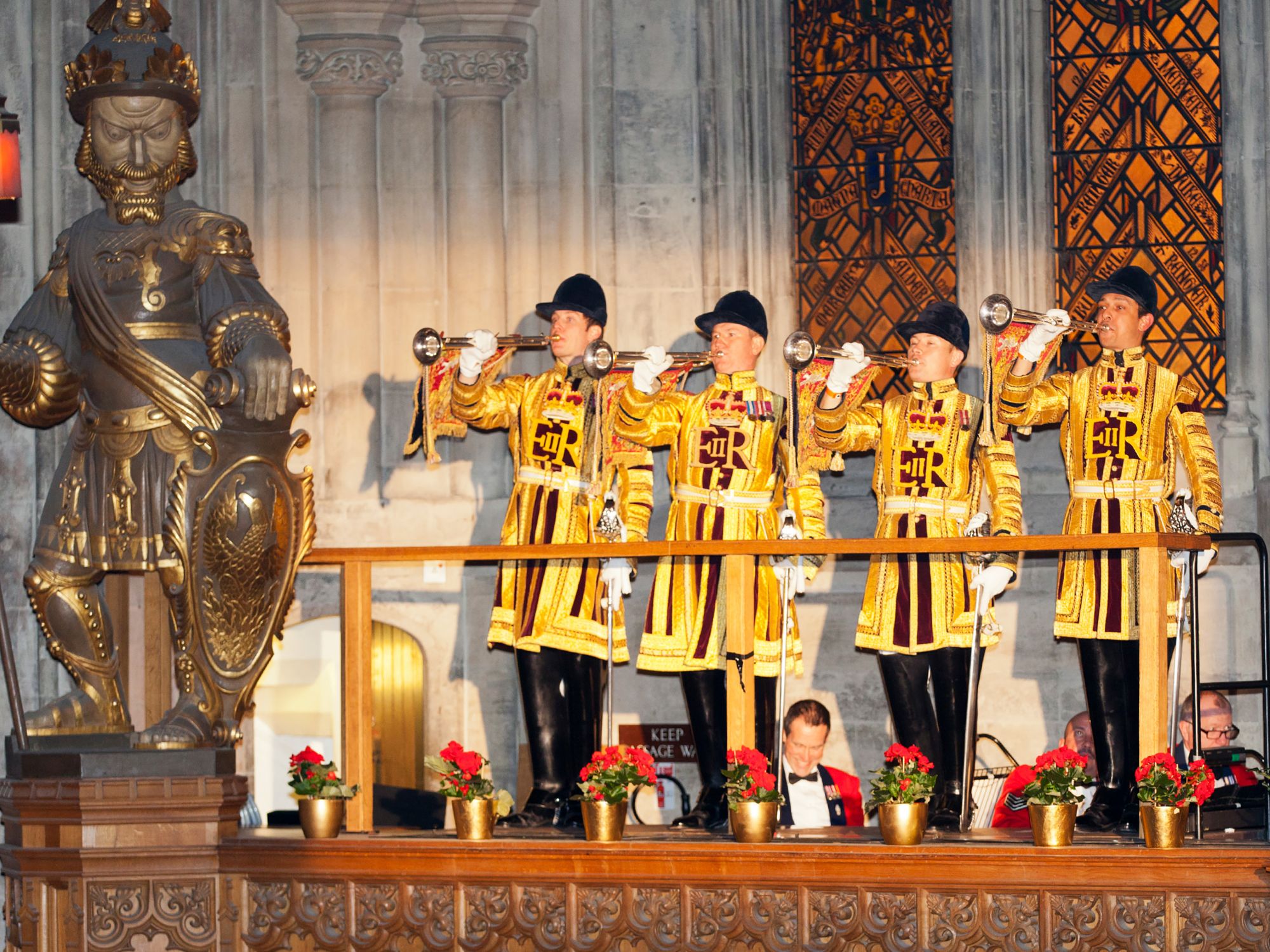 men dressed in royal uniform blowing a horn, standing beside Gog and Magog